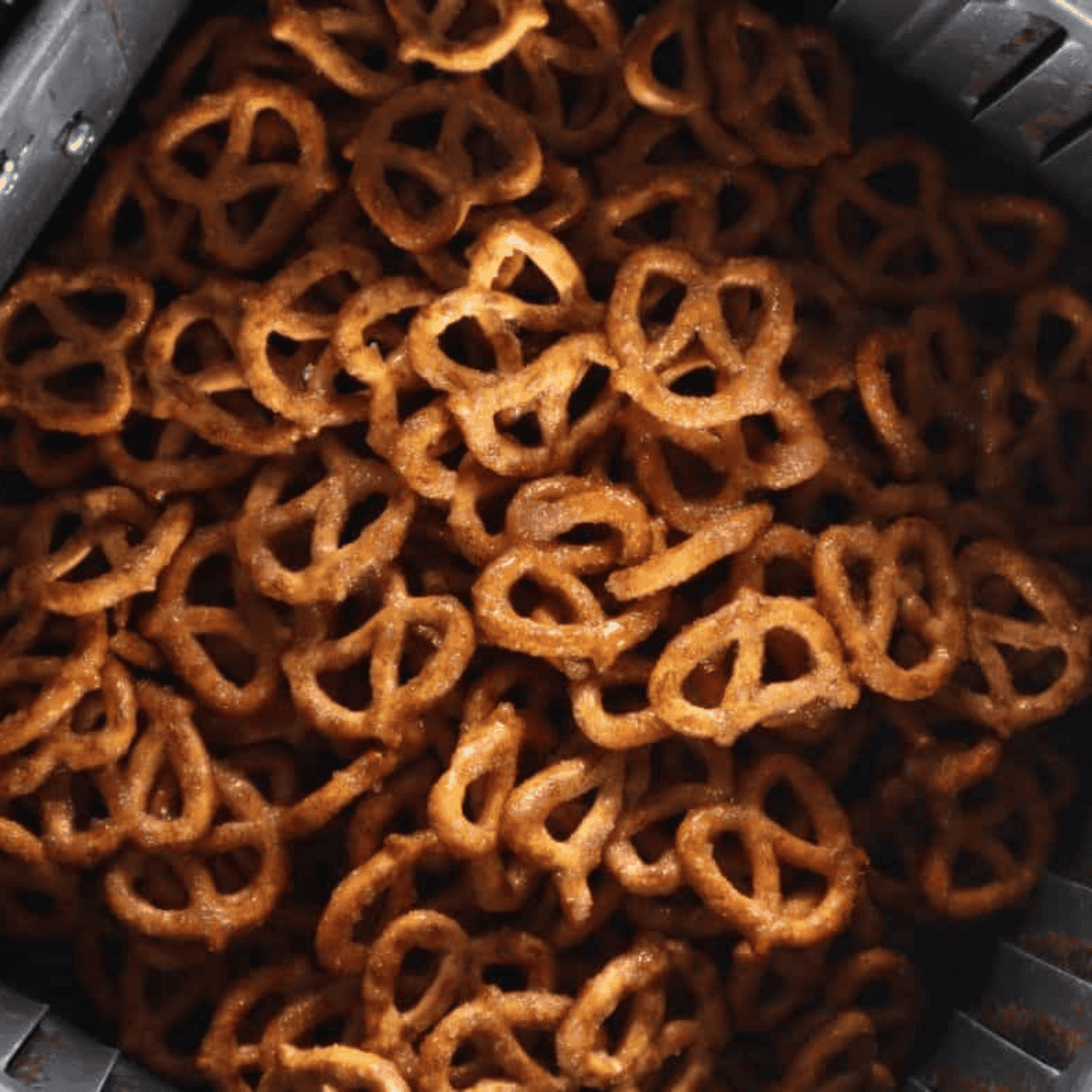 Coated pretzels arranged in a single layer in the air fryer basket before cooking.