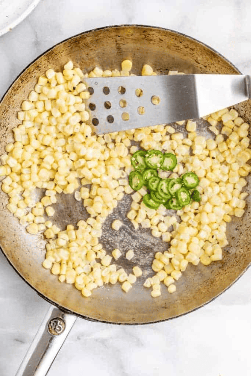 corn kernels cooking in a skillet with melted butter over high heat