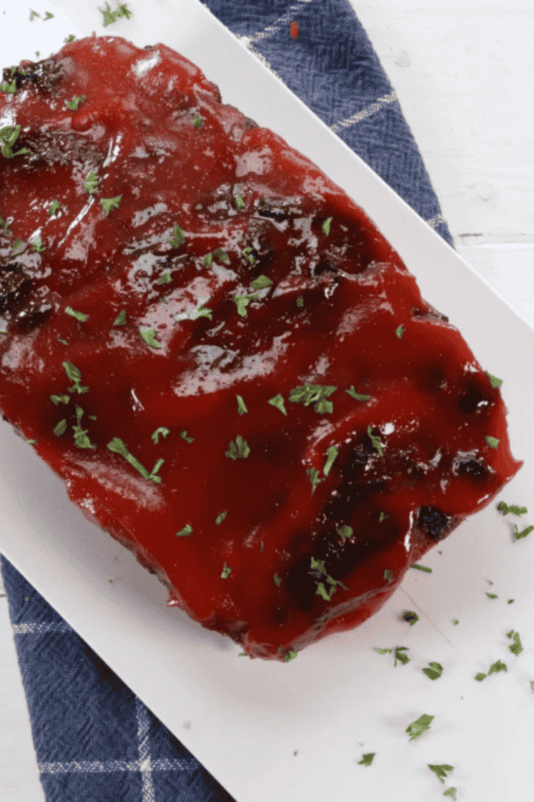 Uncut Boston Market copycat meatloaf on a plate topped with tangy hickory ketchup glaze