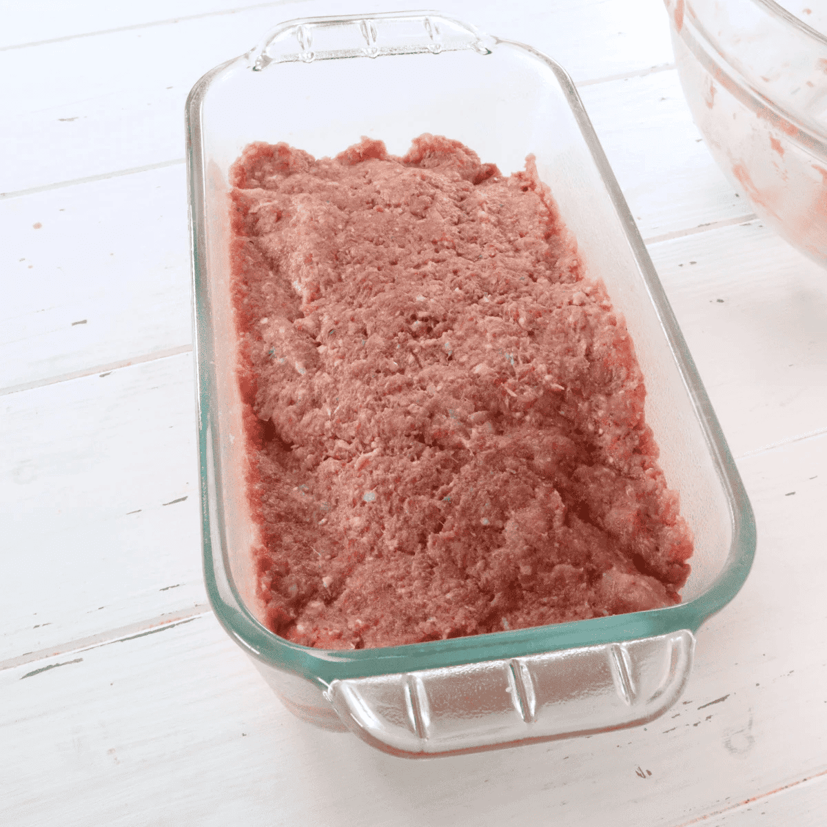 Boston Market copycat meatloaf pressed into a greased loaf pan with hickory ketchup glaze spread on top