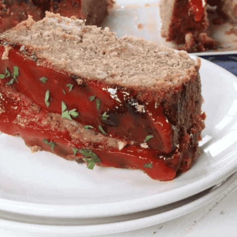 Slice of copycat Boston Market meatloaf on a white plate with hickory ketchup glaze