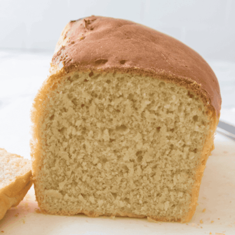 golden brown freshly baked farmhouse white sandwich bread on cutting board