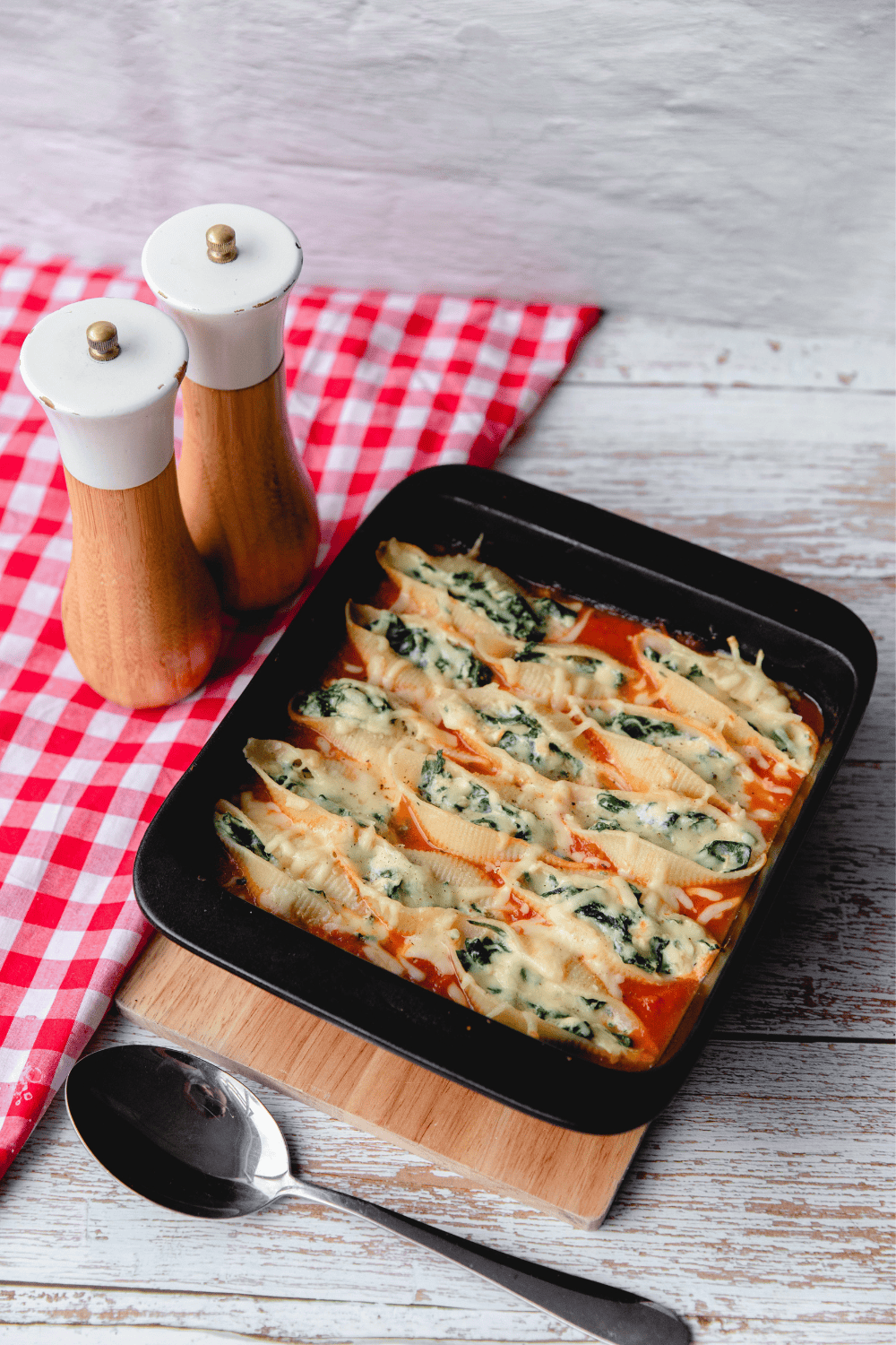 A plate of air fryer stuffed spinach pasta shells topped with melted mozzarella and marinara sauce