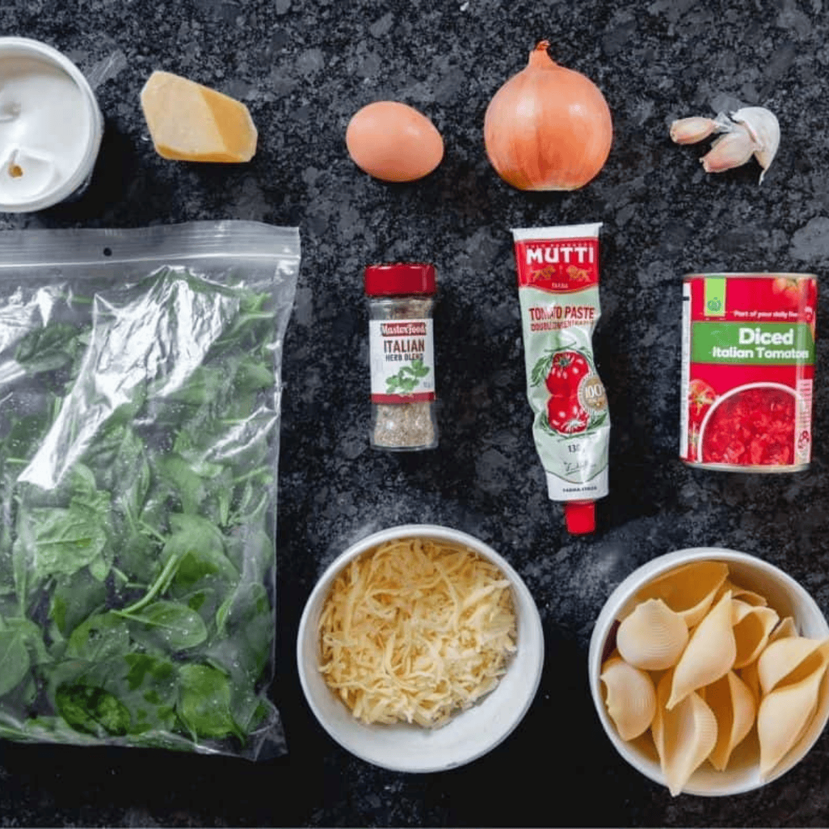 Ingredients for air fryer stuffed spinach pasta shells, including jumbo pasta shells, baby spinach, ricotta, mozzarella, Parmesan, and marinara