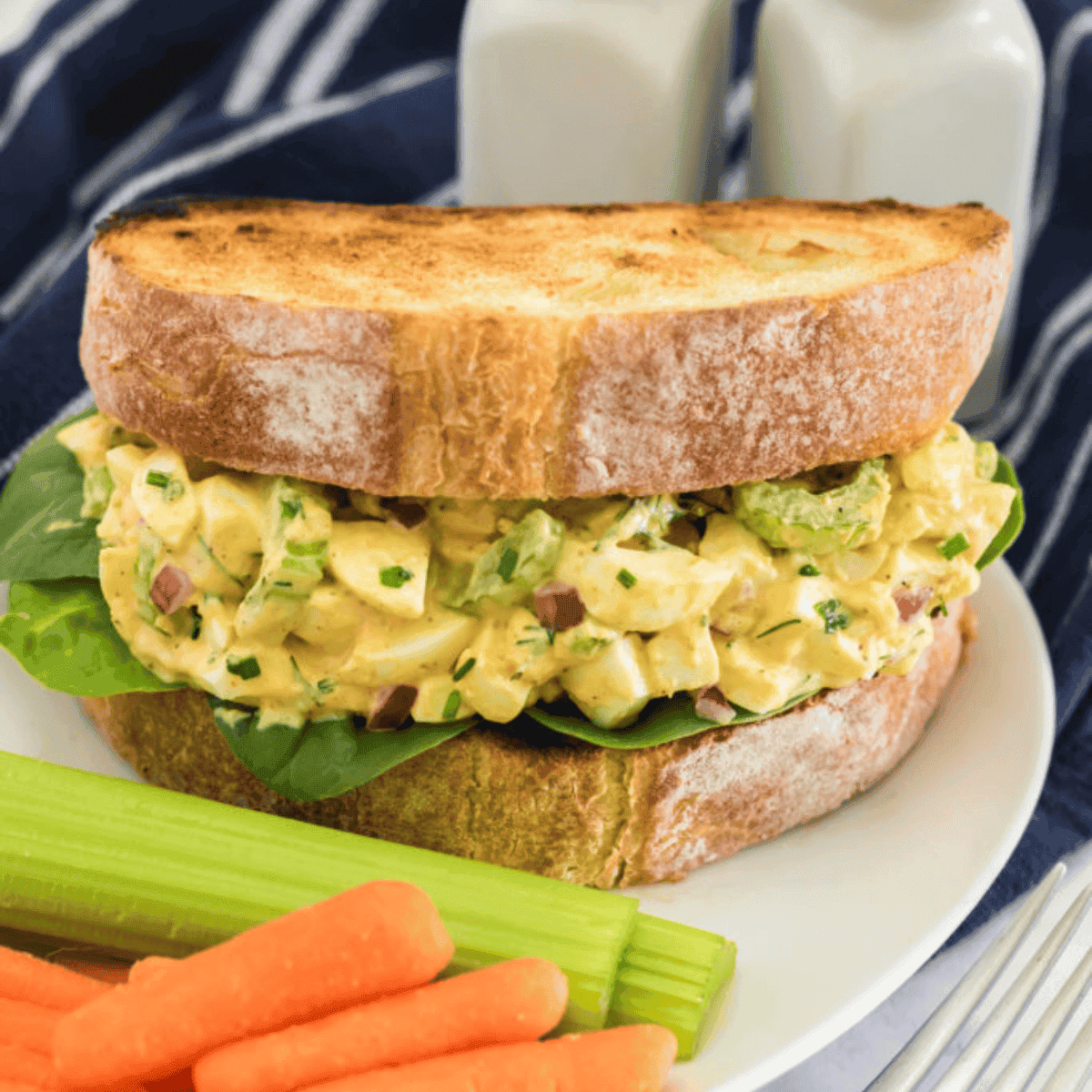 Creamy egg salad with dill pickles served on toasted bread with lettuce, ready to enjoy as a sandwich or light meal.