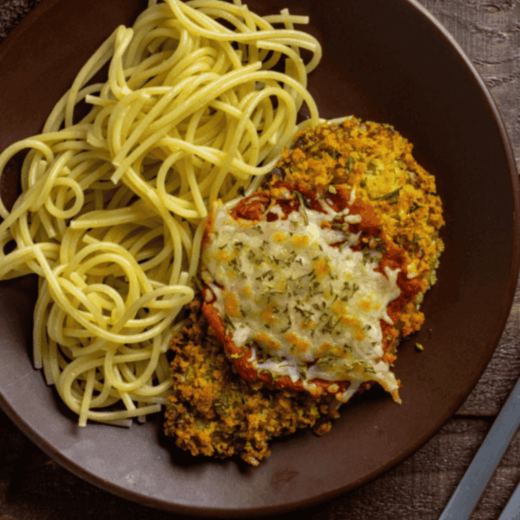 Crispy Easy Air Fryer Veal Parmesan cutlet topped with melted mozzarella cheese and marinara sauce on a plate.