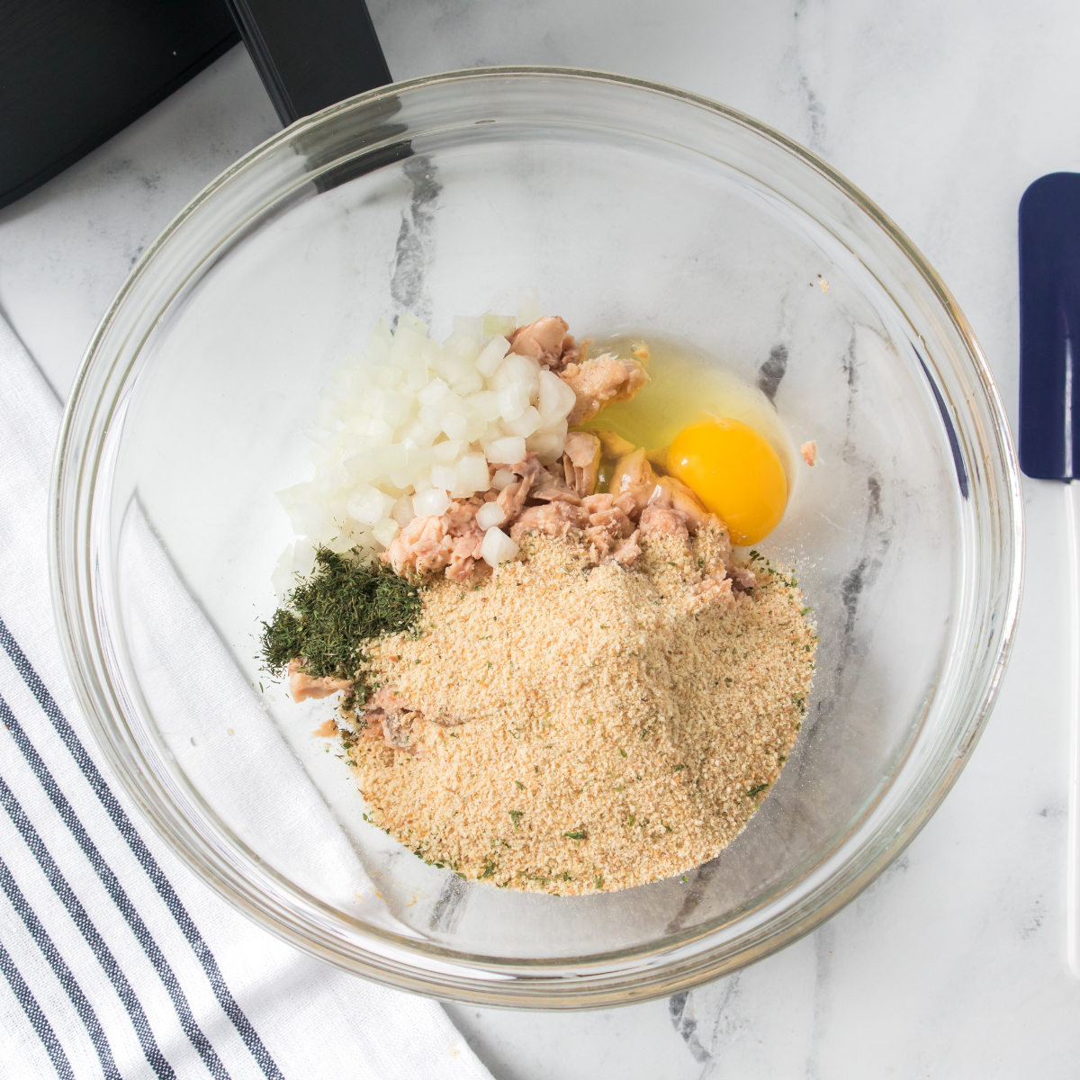 Fresh salmon burger mixture in a large bowl with chopped salmon, panko breadcrumbs, egg, herbs, scallions, and seasonings gently mixed together before shaping patties
