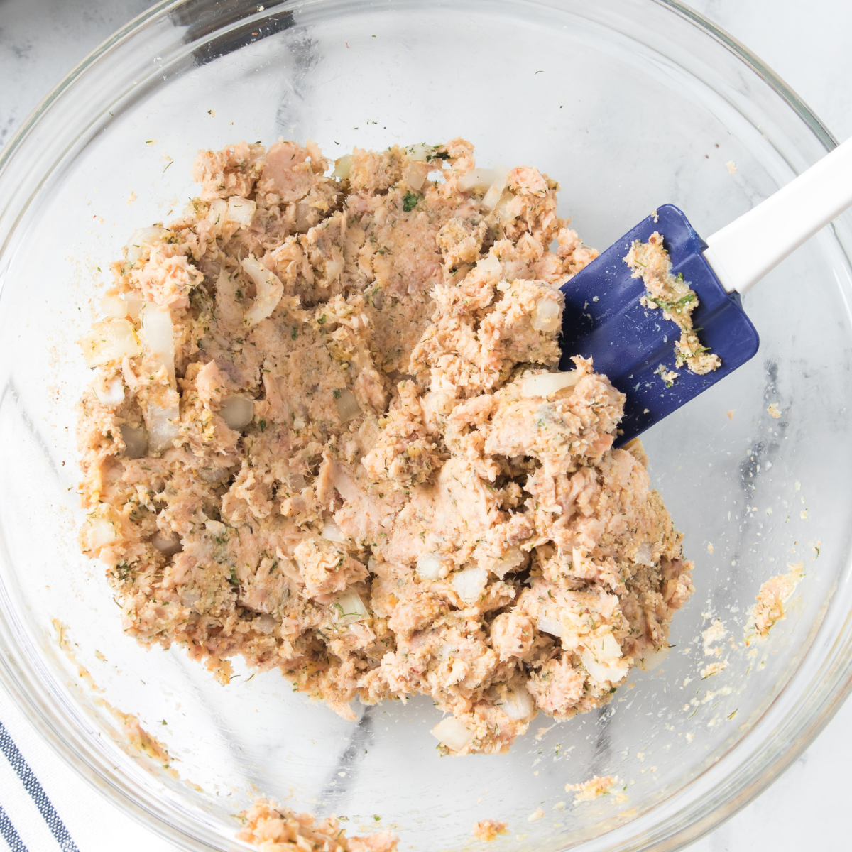 Salmon burger patties shaped by hand on parchment paper with thumb indent in center before air frying