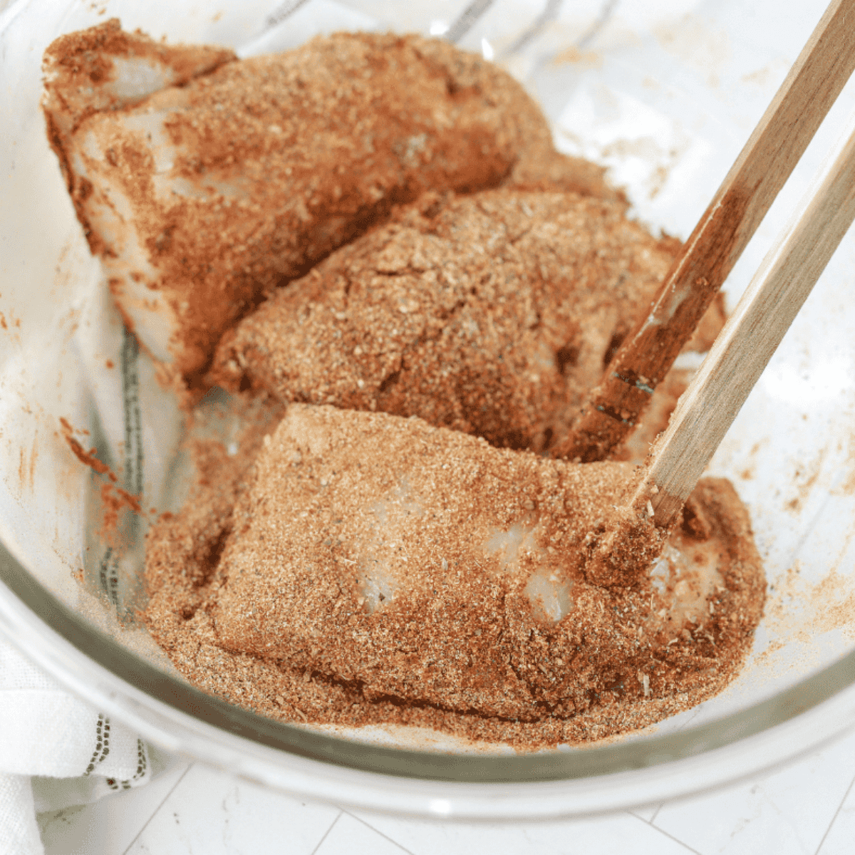 Red snapper fillets being dipped in melted butter and coated with Cajun seasoning