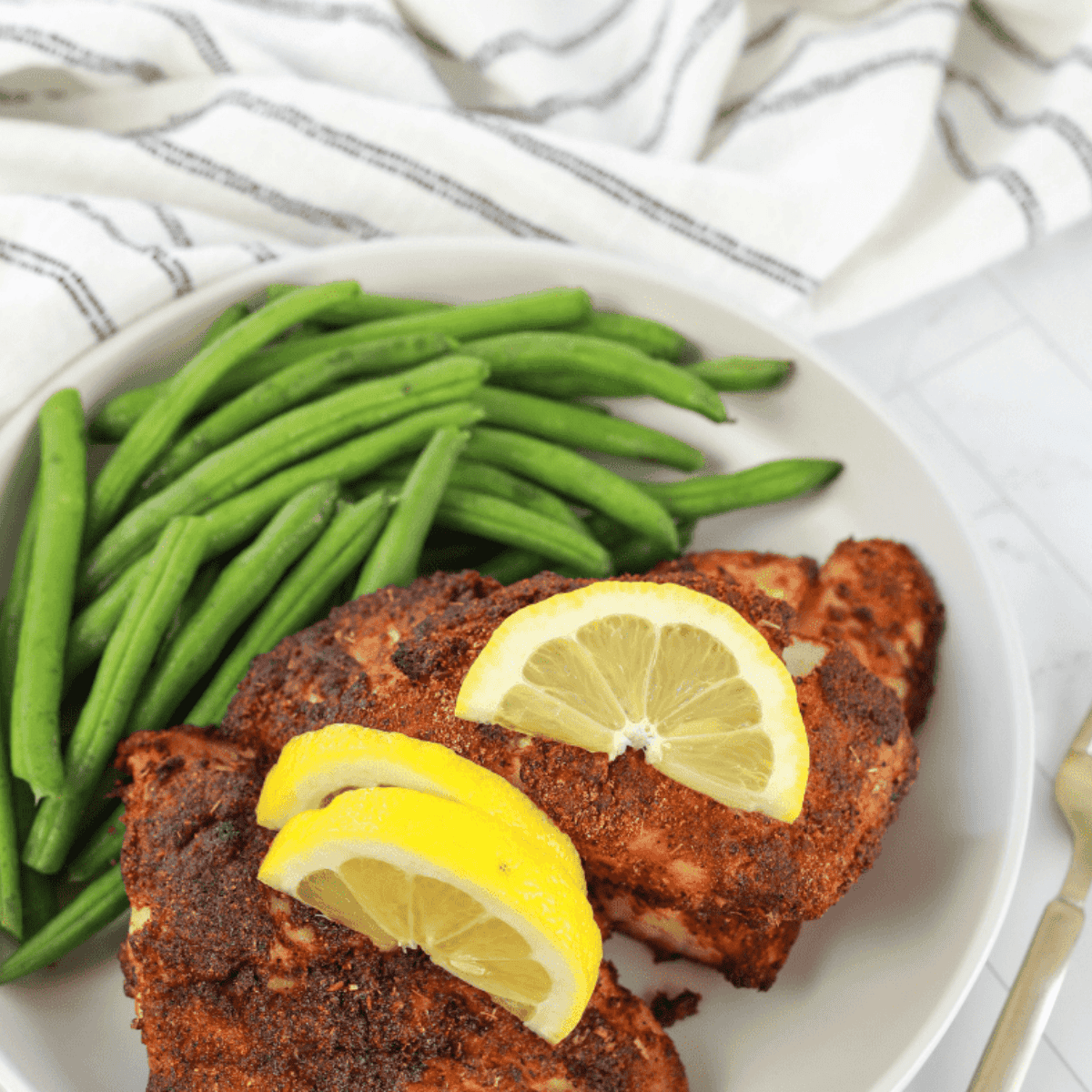 Golden, flaky air fryer red snapper fillet served with lemon and herbs