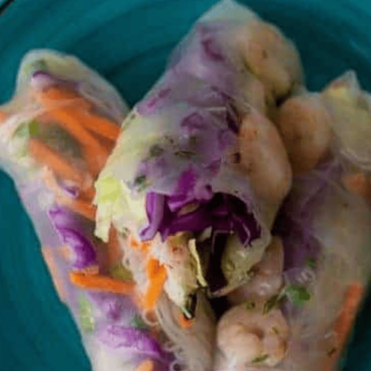 Golden crispy air fryer rice paper rolls filled with prawns and vegetables, served with dipping sauce.