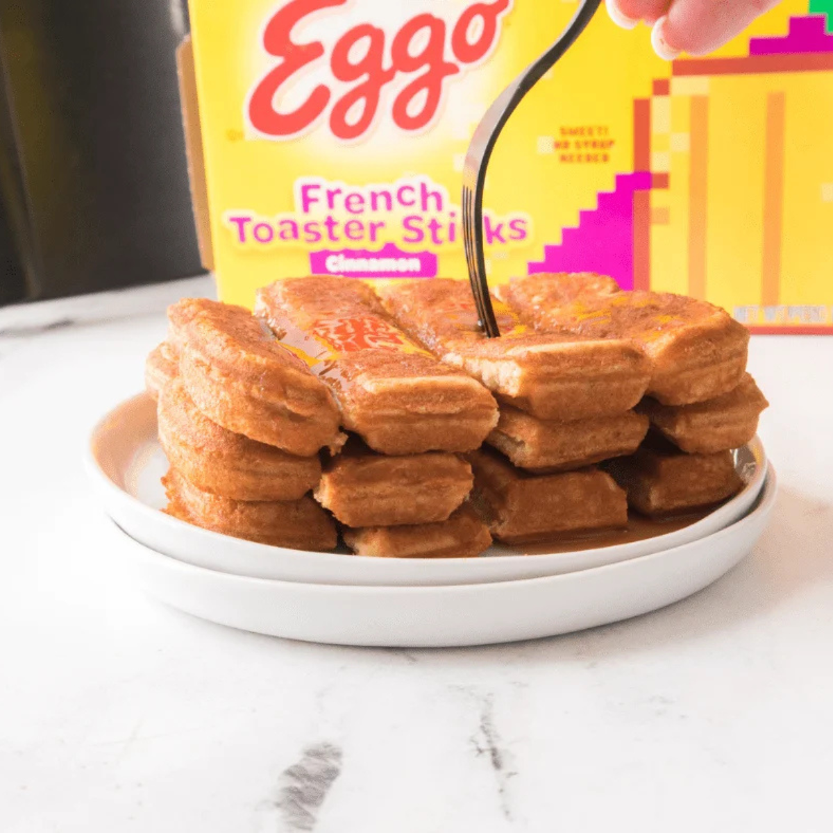 Golden crisp air fryer Eggo French Toast Sticks on a plate with maple syrup drizzled over them
