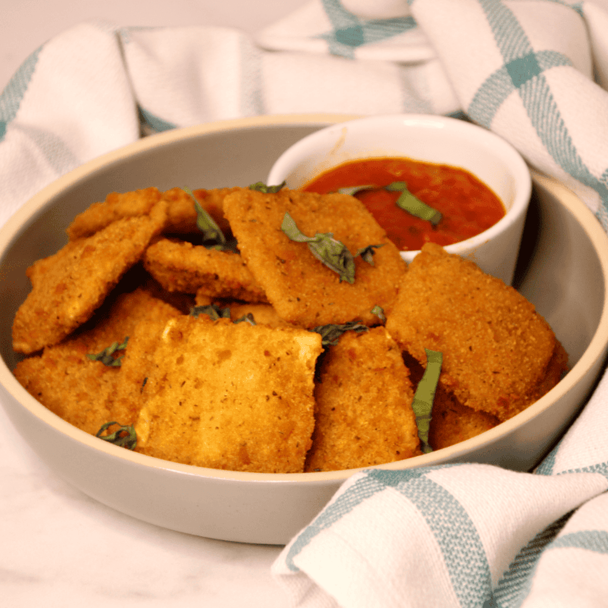 Crispy air fryer breaded ravioli served on a plate with dipping sauce