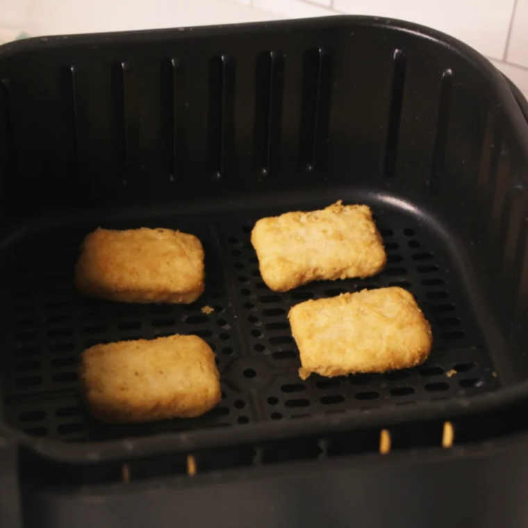 Frozen Trader Joe's battered fish nuggets in a single layer in an air fryer basket