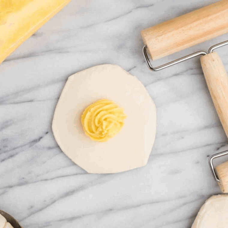 Piping Bavarian cream into rolled biscuit dough for donuts