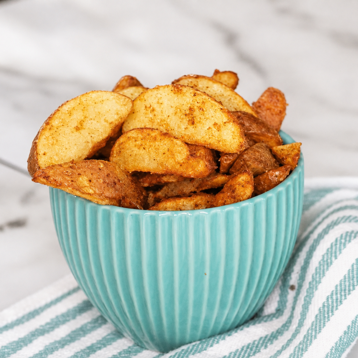 Crispy golden air fryer frozen potato wedges served in a blue bowl