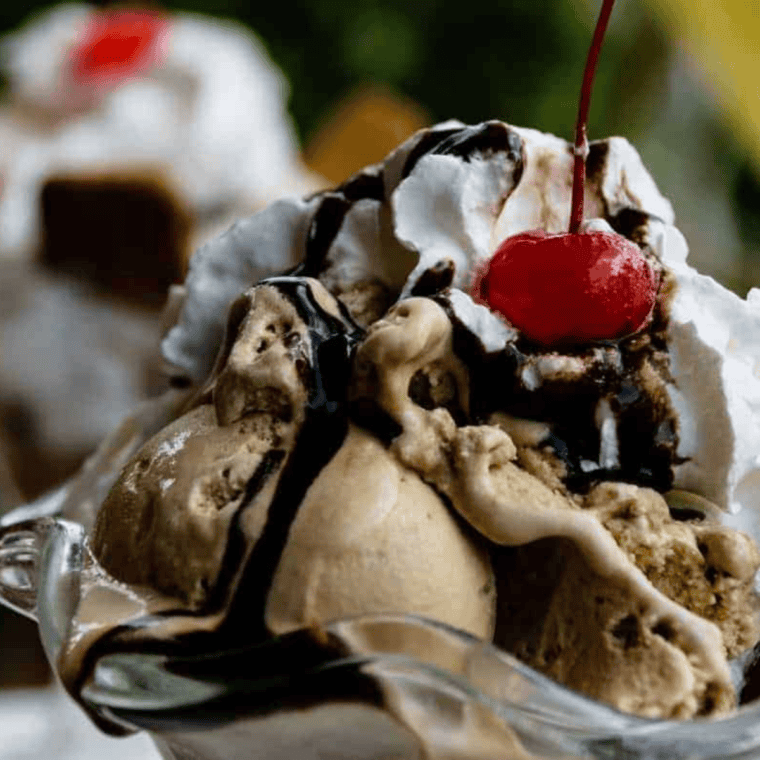 Homemade copycat Hershey’s chocolate syrup drizzled over vanilla ice cream in a bowl
