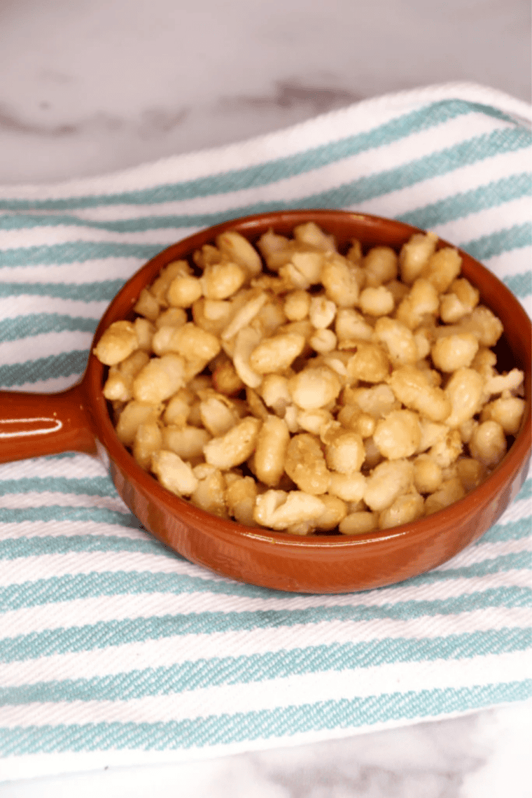 Crispy air fryer cannellini beans in a white bowl after cooking, golden brown and blistered