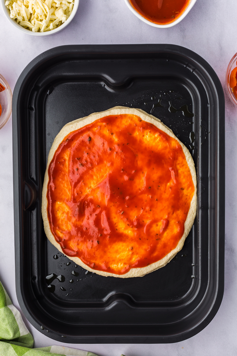 Spreading a thin layer of tomato sauce evenly over Boboli pizza crust”