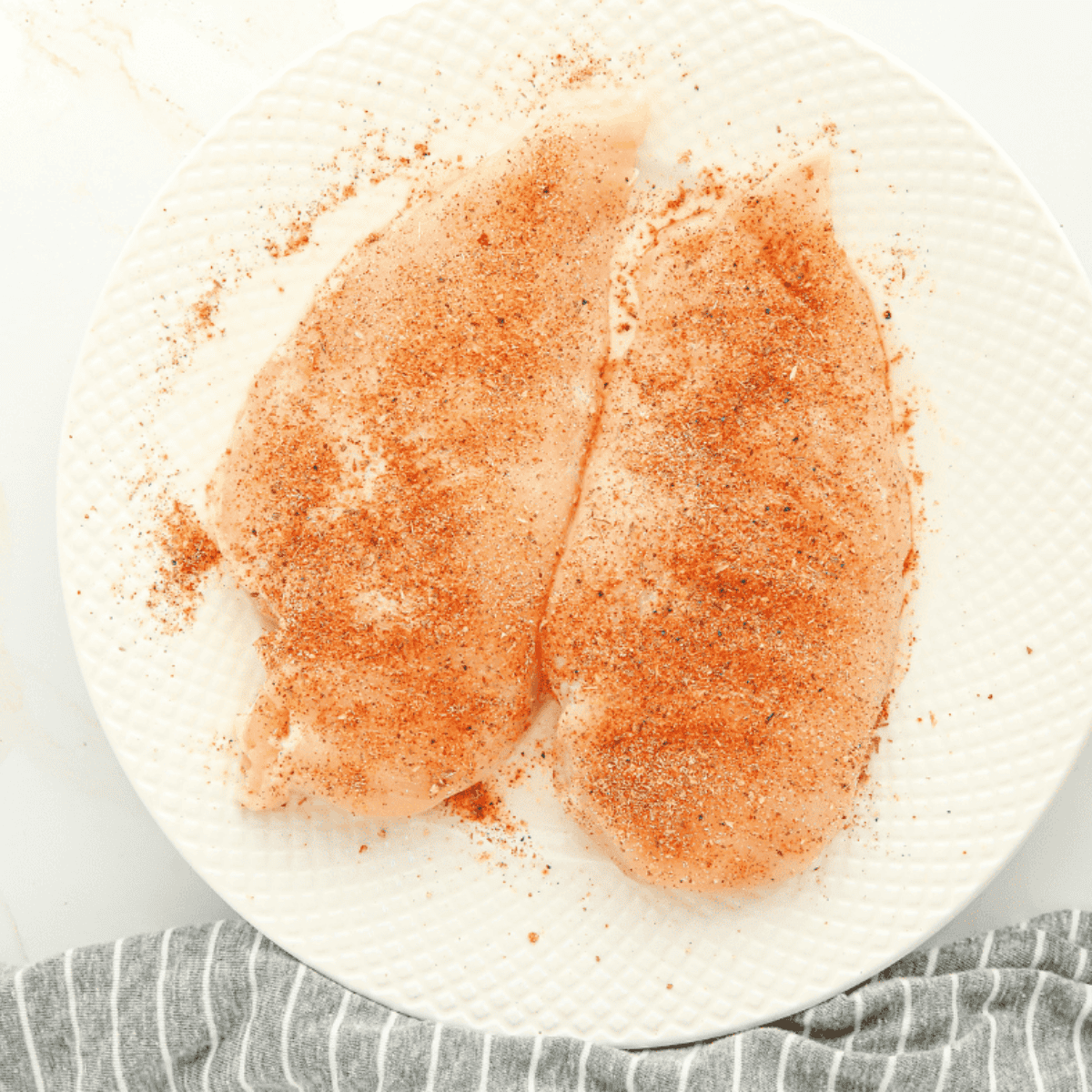 Air fryer Cajun chicken breasts seasoned evenly with spice blend before cooking