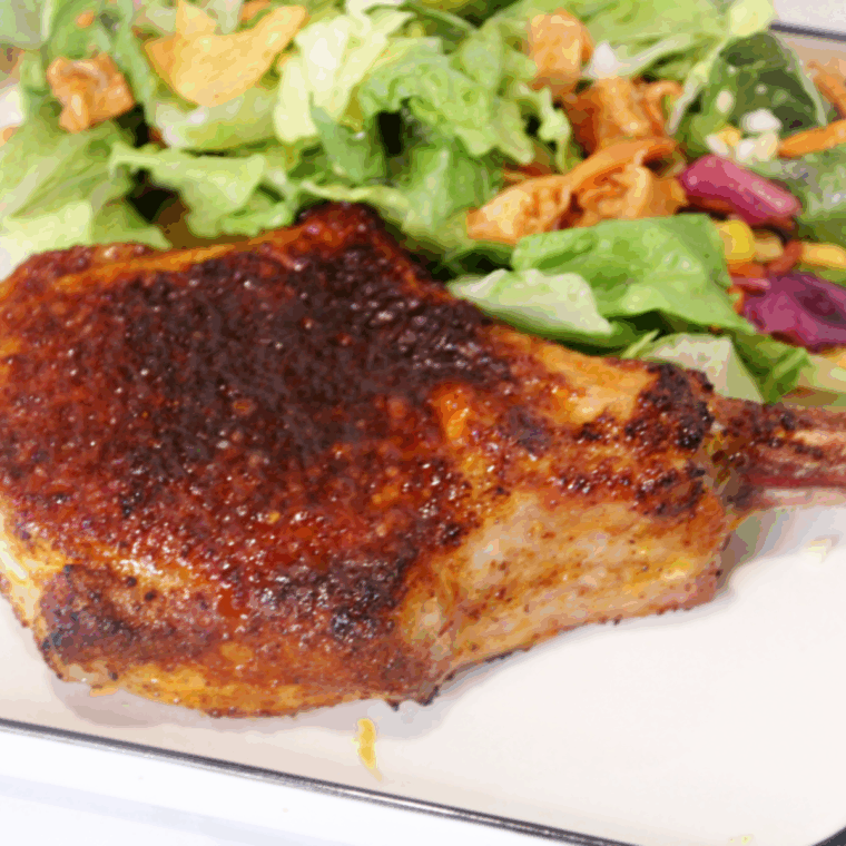 Air Fryer Chile Lime Pork Chop served on a plate with lime wedges and fresh herbs.