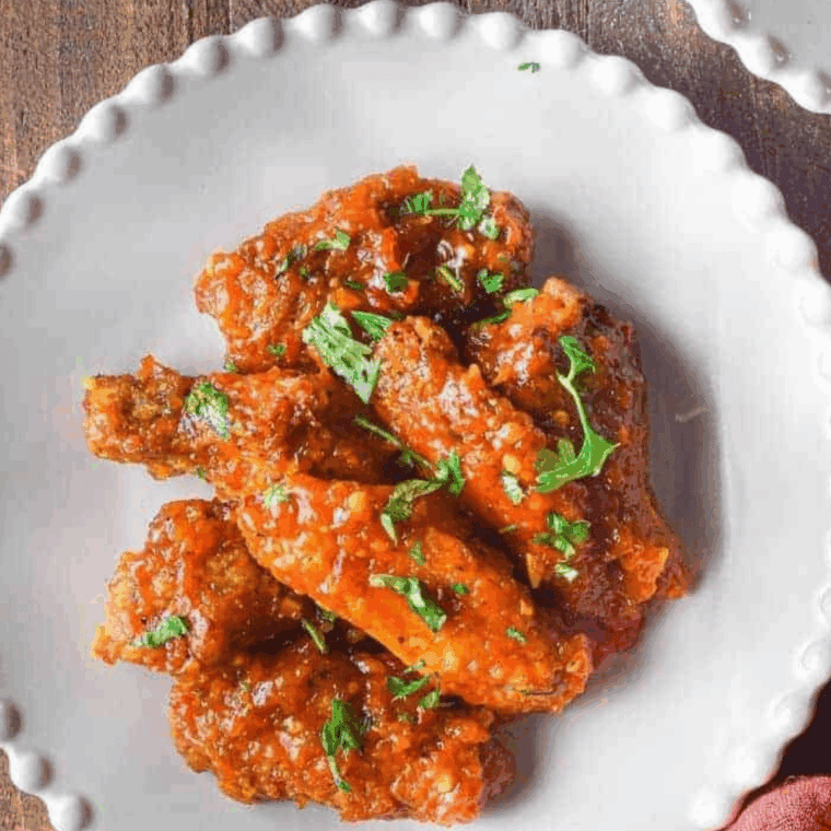 Plated sweet chili chicken wings served with a side of dipping sauce.