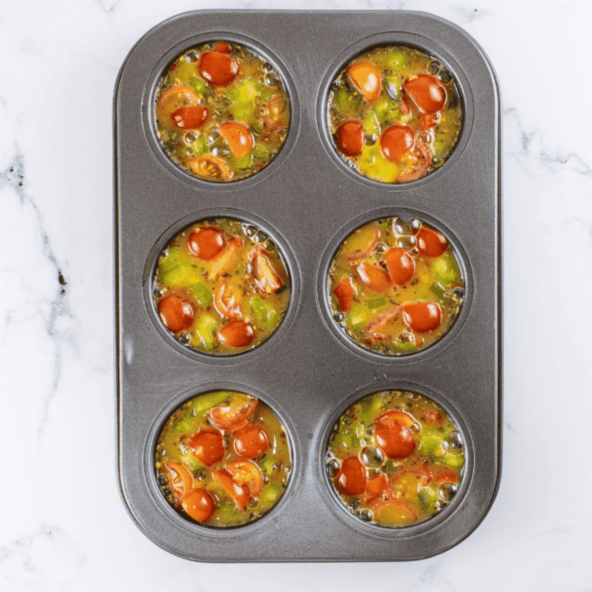 Pouring whisked egg mixture carefully into muffin cups almost to the top