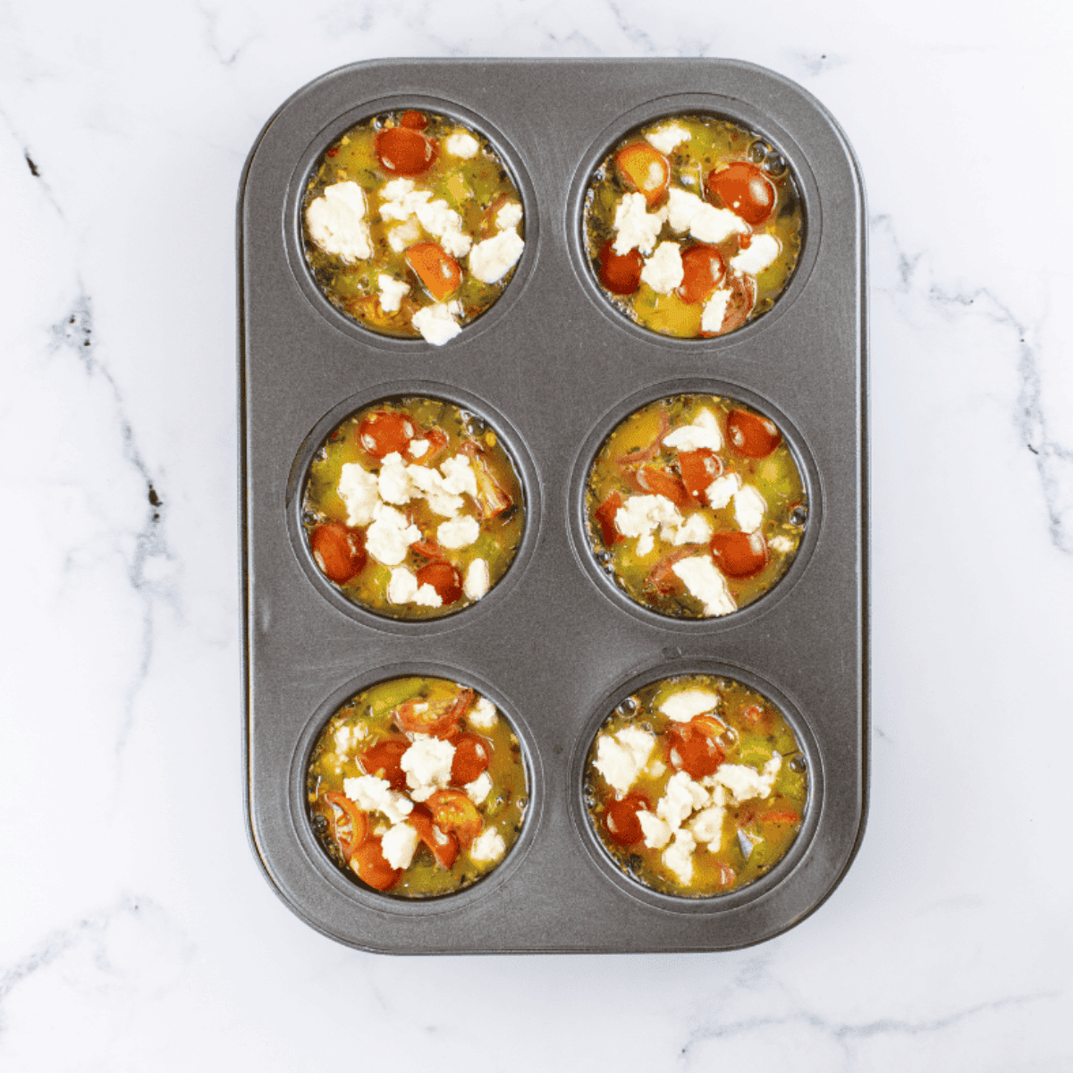 Sprinkling crumbled feta over muffin cups and air frying until golden brown