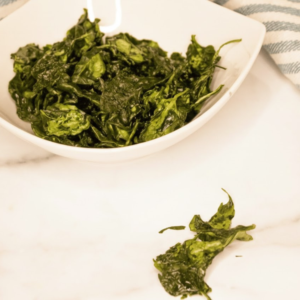 Crispy air fryer spinach chips in a bowl, lightly seasoned and golden green.