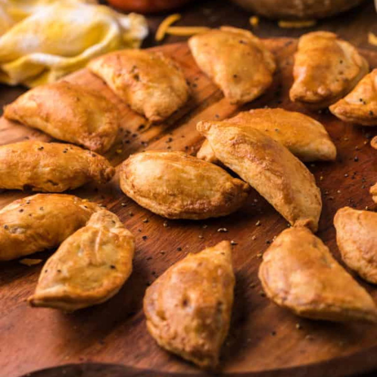 Golden air fryer beef empanadas stacked on a white plate with salsa for dipping