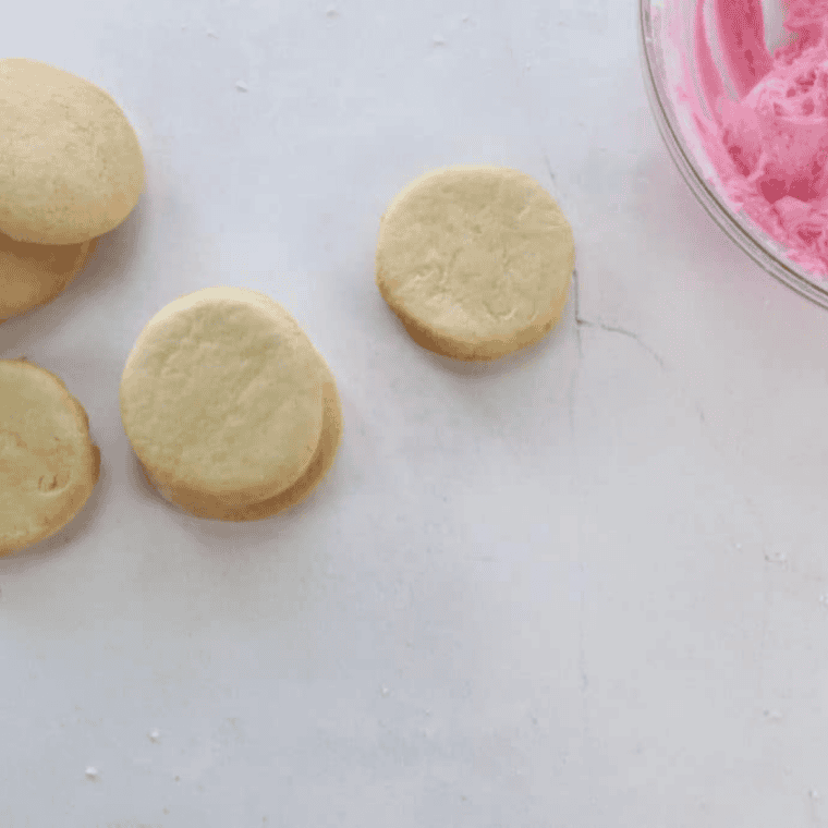 Air fryer Lofthouse cookies being frosted and decorated with colorful sprinkles.
