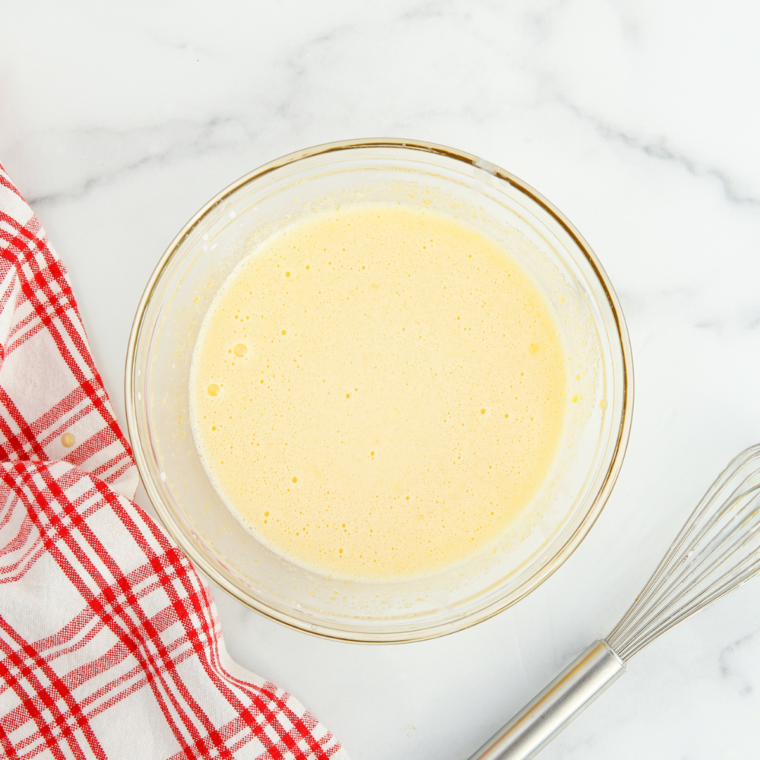 Egg yolks and granulated sugar whisked smooth in a glass mixing bowl