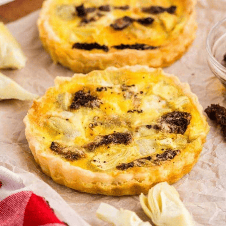 Air fryer sun-dried tomato and artichoke quiche, sliced and served on a white plate.