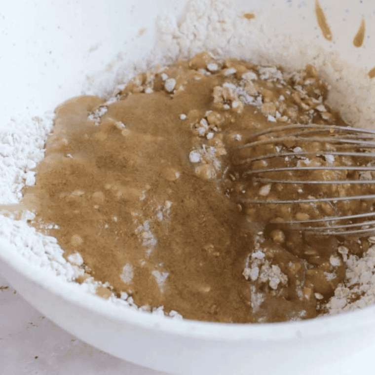 Combining wet apple mixture with dry ingredients and folding in chopped apples for cookie dough.