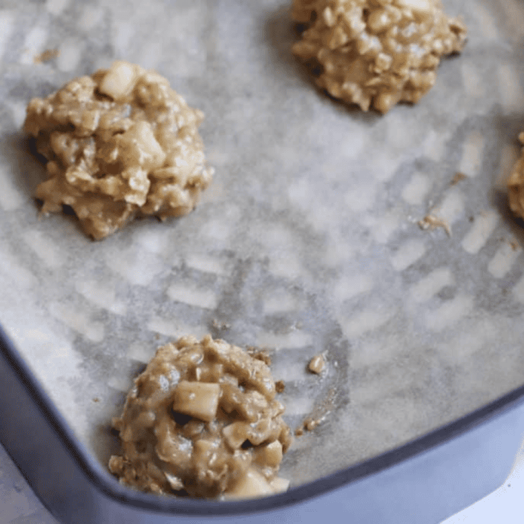 Scooping two-inch cookie dough balls onto parchment-lined air fryer basket, preheating to 315°F