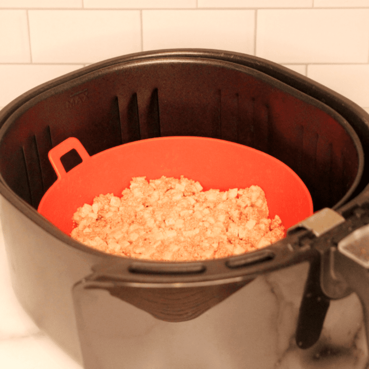 Canned corned beef hash being cooked and stirred in air fryer basket