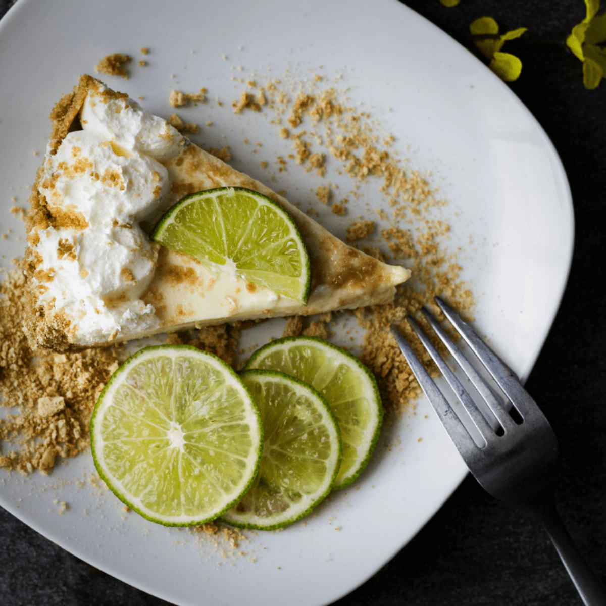 Dehydrated lime slices arranged on a wooden board with fresh limes