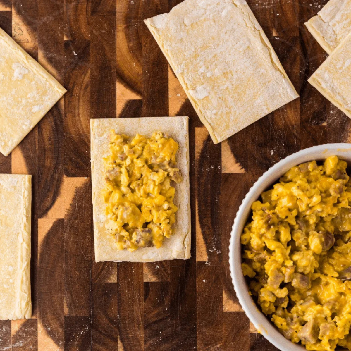 Unfolded puff pastry sheet placed on a lightly floured cutting board before cutting