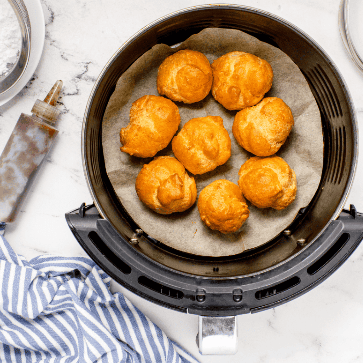 Cooked Sufganiyot in the air fryer basket.