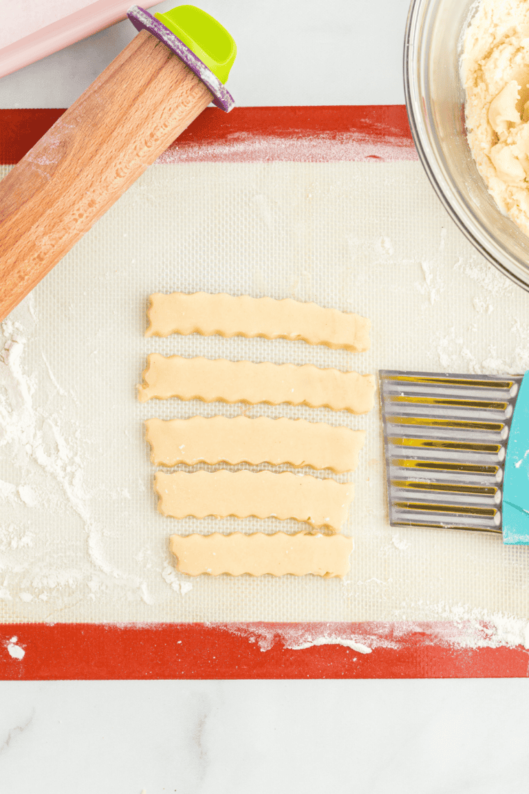 Rolling out snickerdoodle cookie dough to 3/8” thickness on lightly floured surface using a rolling pin for even, thick, chewy cookies.