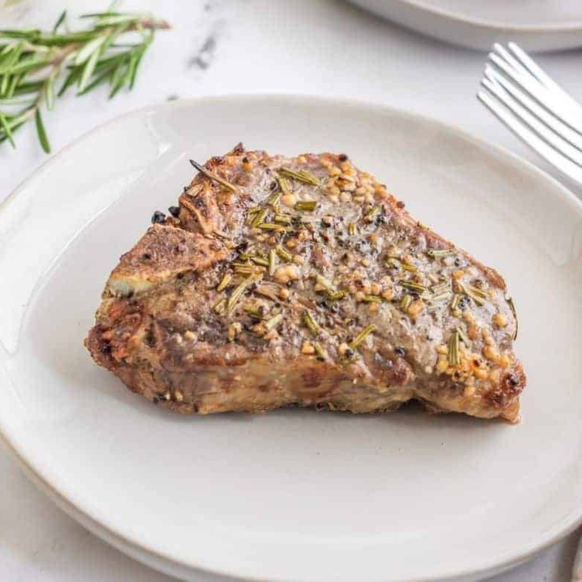Frozen lamb chops in the air fryer, cooked golden-brown and garnished with fresh rosemary