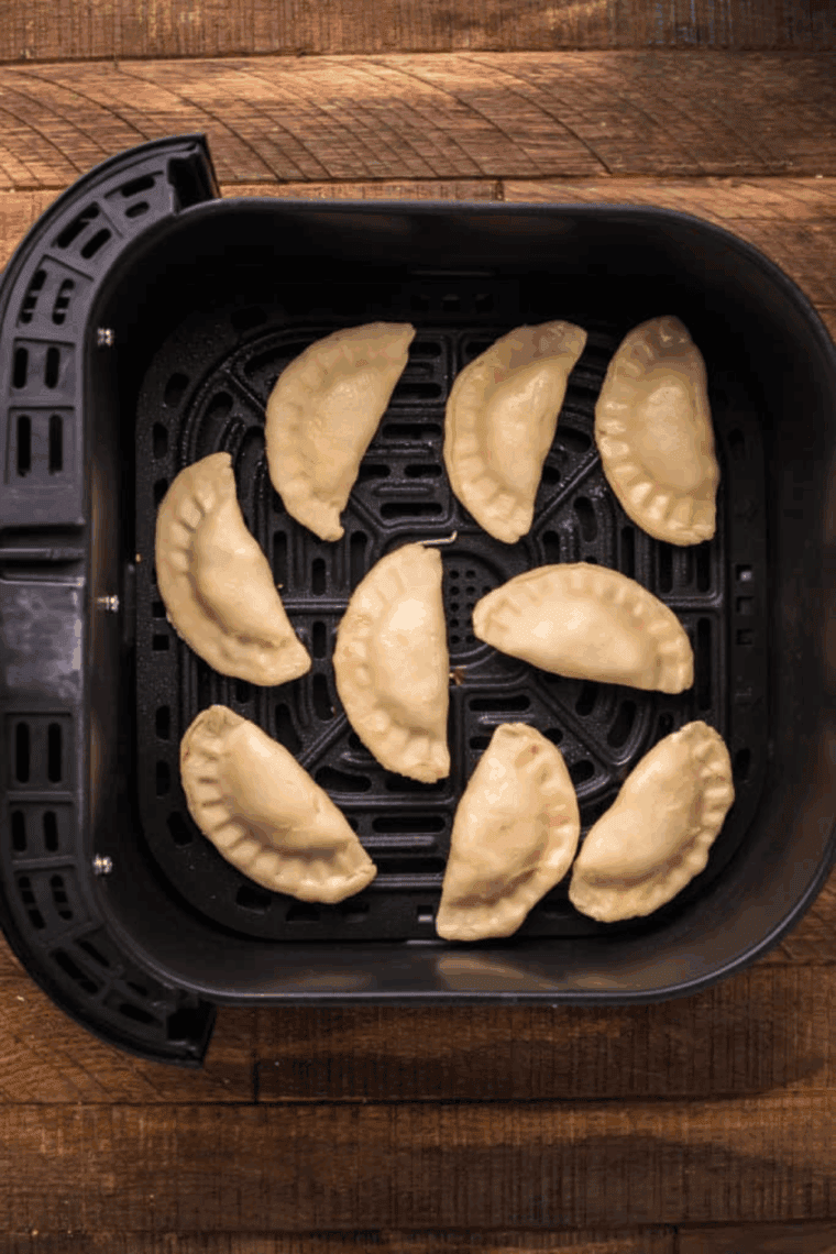 Brushed meat pies with melted butter and a sprinkle of pepper, ready to cook in the air fryer at 330°F for 5–7 minutes.