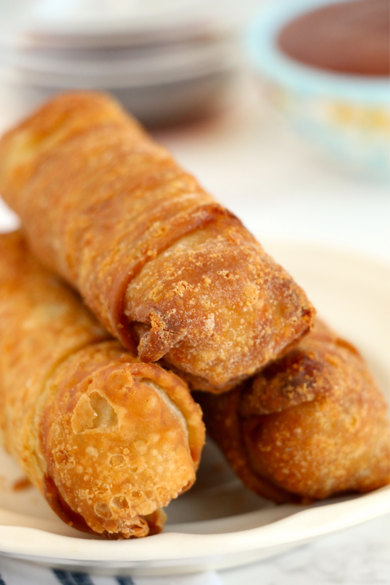 Crispy golden Pagoda egg rolls stacked on a plate with dipping sauce