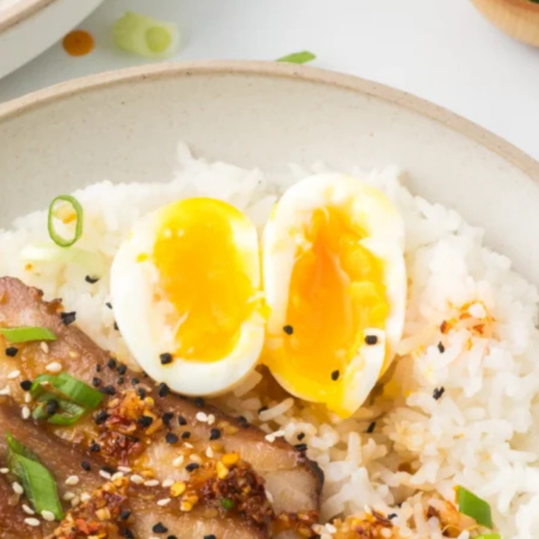 Air fryer jammy egg halved showing golden custardy yolk on white plate