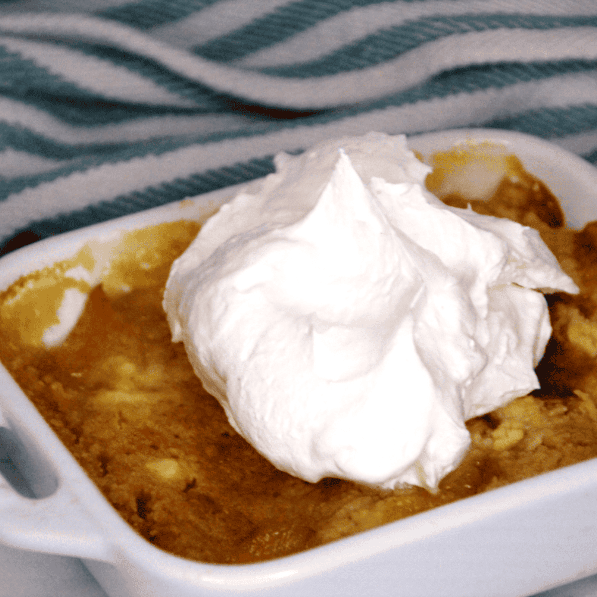 Air fryer peach dump cake in a ramekin with golden cake topping and juicy peaches underneath, ready to serve.