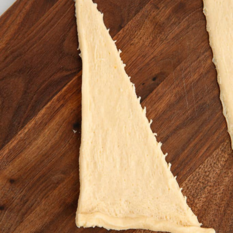 Crescent roll dough unrolled on a cutting board and separated into eight triangles