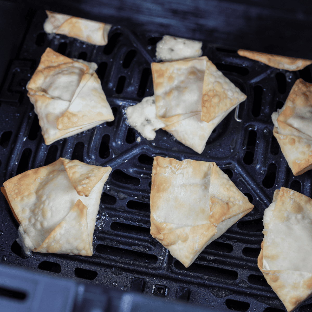 Air fryer set to 350°F preheating on a countertop, empty basket ready for reheating crispy crab rangoon.