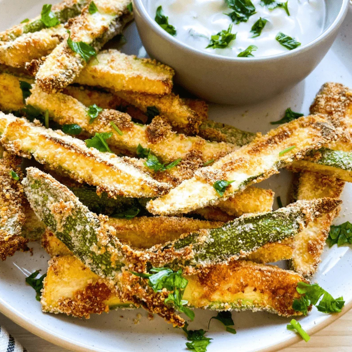 Crispy keto air fryer zucchini fries with golden parmesan coating served with ranch dipping sauce