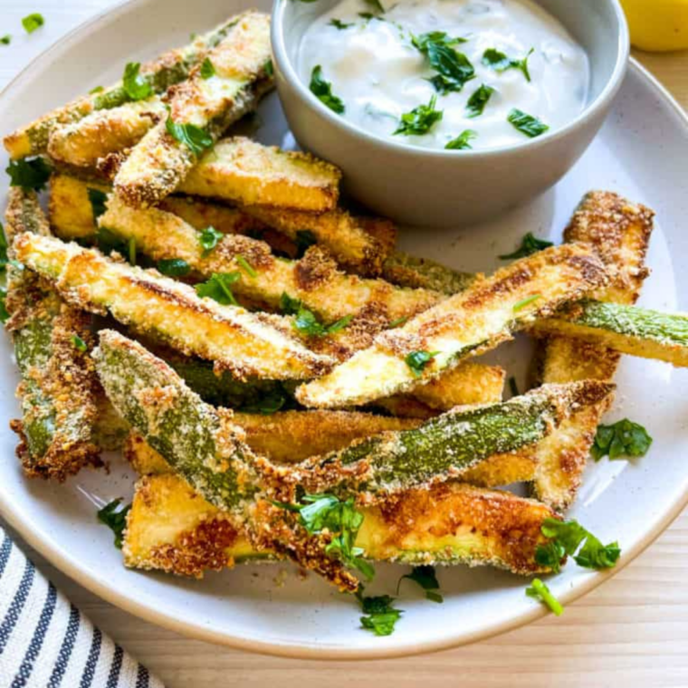 Golden brown zucchini fries in the air fryer basket after cooking at 400 degrees