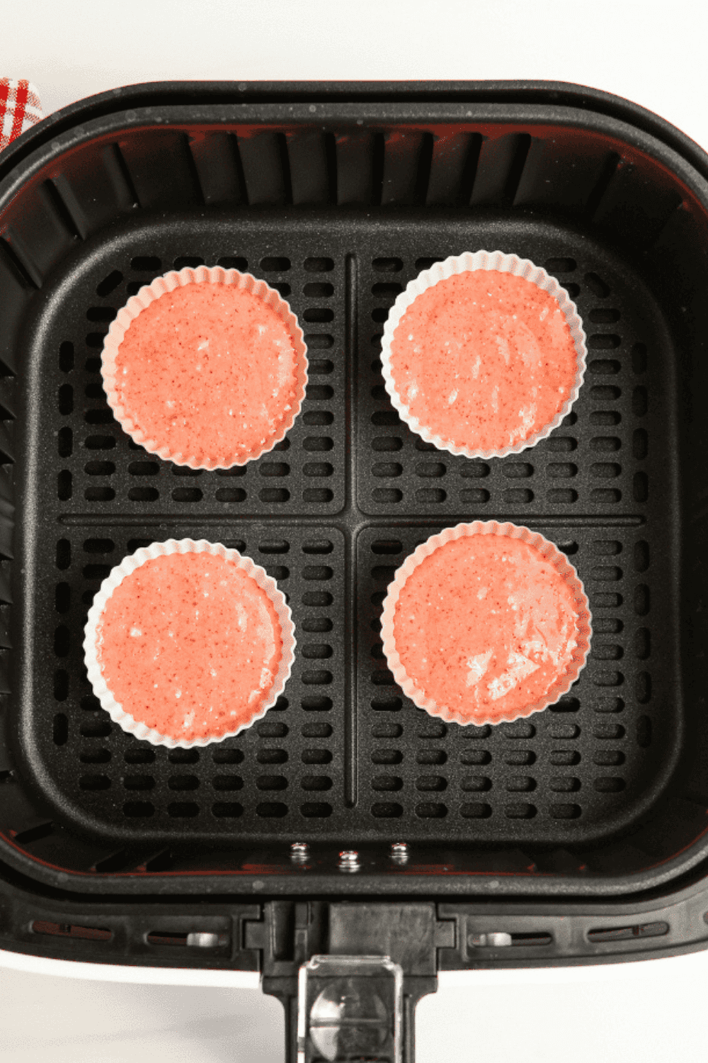 Lined strawberry cupcakes placed in the air fryer basket before baking.